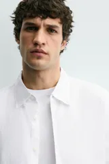 Camisa blanca de lino de corte regular fit, con cuello abotonado, manga larga y cierre frontal de botones.