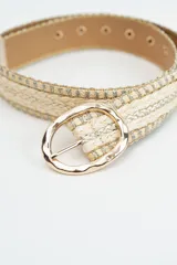 Cinturón de estilo trenzado en tonos beige y dorado, con hebilla metálica ovalada de acabado irregular.
