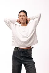 Remera de silueta amplia con hombro caído y cuello redondo, confeccionada en tejido suave de algodón. Presenta un diseño holgado y versátil con mangas largas.