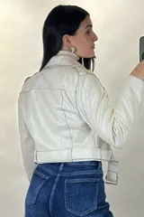 Chaqueta corta tipo biker confeccionada en gamuza color beige, con cierre frontal cruzado, solapas amplias, bolsillos con cierre y cinturón ajustable en la cintura.