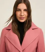 Saco largo negro confeccionado en polivelour, con solapas en el cuello, trabillas en los laterales de la cintura y cinturón franja de tejido.