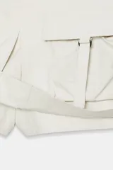 Falda pantalón satinada de tiro medio y color negro, con bolsillos cargo de plastrón con solapa, pliegues decorativos en el delantero y cierre lateral con cremallera oculta.