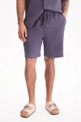 Bermuda de muselina color gris oscuro, con corte holgado tipo baggy y cintura elástica con cordón de ajuste.