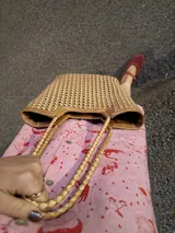 Bolso tipo tote bag de cuero trenzado a mano, en tonos marrón y negro, con asas trenzadas.