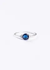 Anillo de plata 925 con una zirconia azul central y pequeñas zirconias blancas a los lados.