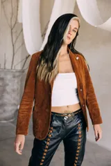 Blazer de gamuza color marrón oscuro, con solapas de muesca, cierre frontal de dos botones grandes claros y bolsillos frontales ribeteados.