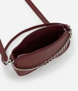 Cartera tipo baguette color bordó, confeccionada en poliuretano con acabado liso. Presenta una cadena decorativa plateada en el frente, cierre superior con cremallera y correa larga ajustable y desmontable.