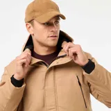 Parka color beige con capucha, cierre frontal con cremallera y botones a presión, bolsillos laterales con solapa y bolsillos superiores con cierre.