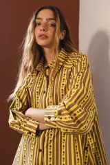 Camisa de manga larga con cuello clásico y cierre frontal de botones. Presenta un diseño de rayas verticales verdes y blancas con un estampado lineal de pequeñas flores rojas.