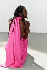 Vestido largo fucsia de cuello halter, espalda descubierta y cierre lateral con cremallera oculta en costura.