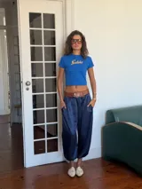 Pantalón de corte holgado y tiro alto, confeccionado en tela satinada color marrón oscuro. Presenta cintura elástica con cordón ajustable y diseño amplio en las piernas.