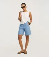 Bermuda regular de cintura alta, confeccionada en jeans, con cintura sastre, trabillas en la cintura y cierre tradicional.