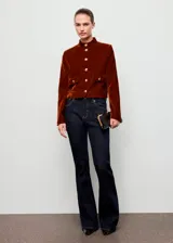 Chaqueta corta de terciopelo marrón con cuello mao, cierre frontal de botones dorados, mangas largas y dos bolsillos delanteros con solapa y botón.