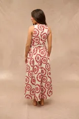Vestido midi sin mangas, con cuello redondo y diseño estampado en tonos rojos y beige sobre base blanca. Incluye un cinturón ajustable de la misma tela en la cintura y falda con vuelo.