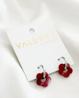 Aros colgantes con aro de acero plateado y dije de acrílico con forma de flor color borgoña.