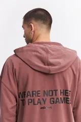 Campera con capucha de algodón con efecto acid wash, corte oversize y estampa gráfica en la espalda con la frase 'WE ARE NOT HERE TO PLAY GAMES' y logo de la marca Mistral.