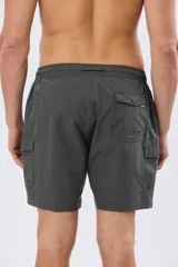 Short de baño cargo color negro, de diseño liso con bolsillos laterales y bolsillos utilitarios con solapa y botón en las piernas. Cuenta con cintura elástica ajustable mediante cordón.