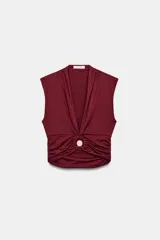 Top de poliamida color bordó con escote en pico, diseño sin mangas y detalle de drapeado frontal con fornitura metálica central.