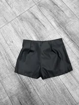 Short negro de cuero sintético con tiro bajo y cordones cruzados en la parte delantera.