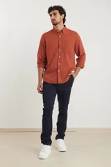 Camisa de manga larga confeccionada en una mezcla de algodón y lino, con cuello abotonado, bolsillo frontal en el pecho y cierre de botones.