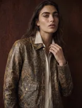 Jacket de cuero color camel con acabado envejecido, diseño estructurado con solapas, cierre frontal con broches a presión y bolsillos frontales con solapa.