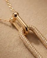 Collar de bronce con baño de oro, diseño de cadena con pequeñas cuentas esféricas y un dije colgante en forma de eslabón alargado completamente pavimentado con circonias.