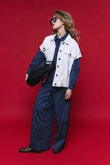 Chaleco de jean color blanco, de corte oversized, con cuello camisero, bolsillos delanteros con solapa y cierre frontal por botones metálicos.