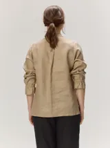 Camisa de lino liviano color tostado, con silueta relajada, cuello mao, alforzas verticales frontales, mangas con volumen y puños elastizados con volados.
