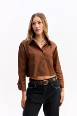 Camisa crop de corte relajado, con cuello clásico, cierre frontal de botones y mangas largas con puños. Confeccionada en algodón, presenta un diseño versátil y moderno.