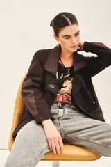 Campera de corte holgado en color marrón oscuro, con cierre frontal mediante broches y jareta interna para ajuste en la cintura. Presenta un diseño con cuello solapa y detalles de costuras visibles.