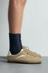 Zapatilla de cordones de estilo retro, con parte superior de serraje color bordó y detalles en piel lisa color rojo. Suela ultrafina de goma en tono marrón oscuro.