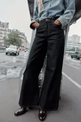 Jeans de denim oscuro, tiro alto, corte pierna ancha (wide leg) y cinco bolsillos. Presenta costuras contrastantes en color claro.