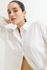 Camisa color crudo, de corte clásico, con cuello camisero, cierre frontal con botones y mangas 3/4 con trabillas.