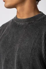 Sweater de punto grueso con textura waffle, de calce relajado y cuello redondo. Presenta puños y ruedo acanalados, con un pequeño parche con logo en el puño izquierdo.