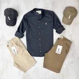 Camisa gris oscura de algodón con cuello mao, manga larga con puños enrollados, cierre frontal con botones y logo bordado en el pecho.