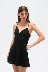 Vestido corto negro de bretel fino, con escote en V, frunces en el busto y cierre en la espalda.