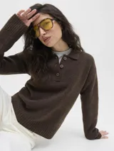 Sweater de punto color beige, con cuello polo y cierre frontal de tres botones, mangas largas con puños acanalados y diseño clásico.