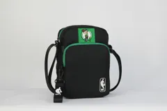 Morral cruzado de nylon negro con ribetes y detalles en verde. Presenta un parche con el logo de los Boston Celtics en la parte superior y un logo de la NBA en la parte inferior frontal. Incluye correa regulable.