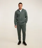 Pantalón deportivo color verde oscuro, confeccionado en tela texturizada de poliéster, con cintura elástica y bolsillos con cierre.