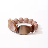Pulsera elástica con cuentas redondas color beige y cuentas irregulares color marrón con efecto marmolado.