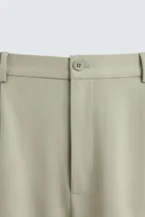 Bermuda de hombre color verde claro, de corte regular y tiro medio, con pinzas frontales, bolsillos laterales y bolsillos traseros de vivo. Cierre frontal con botón y cremallera.