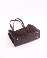 Bolso tipo shopper de gran tamaño, confeccionado en cuero gamuzado color marrón. Presenta estructura rectangular con bordes reforzados en cuero liso oscuro, doble asa de hombro y cierre mediante botón magnético.