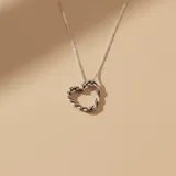 Collar de plata 925 con cadena de eslabones finos y dije en forma de corazón con diseño trenzado.