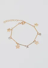 Pulsera dorada con cadena de eslabones, extensión para ajustar el largo y cierre de mosquetón. Presenta dijes colgantes de flores caladas y strass.