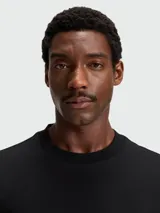 Remera de corte regular, color negro, con cuello redondo y detalle de monograma metálico en el pecho.