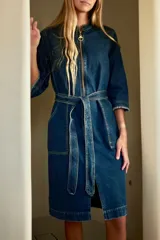 Trench de jean elastizado azul con cierre delantero, frunce en la cintura y lazo para atar.