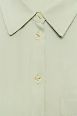 Camisa de corte oversize color marrón, con cuello solapa, mangas anchas por debajo del codo y bolsillo delantero de plastrón. Cierre frontal con botones.