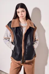Chaleco negro de cuero sintético con interior de piel sintética color beige, cierre frontal con cremallera y corte oversize.