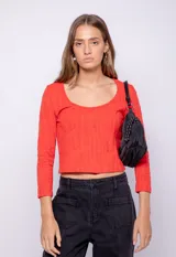 Top rojo de manga larga y cuello redondo con textura sutil en relieve, corte ajustado.