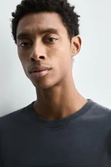 Camiseta relaxed fit de algodón ligero, color gris oscuro, con cuello redondo y manga corta con acabados irregulares. Pertenece a la colección especial Origins.